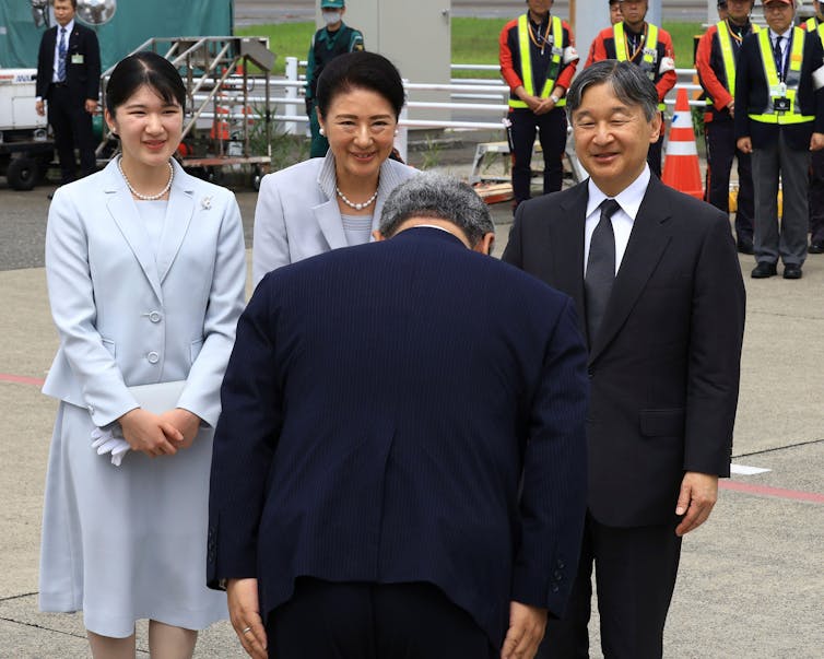 Emperor Naruhito, Empress Masako and their daughter, Princess Aiko are greeted by a man who bows his head.