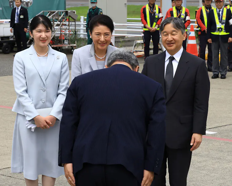 Emperor Naruhito, Empress Masako and their daughter, Princess Aiko are greeted by a man who bows his head.