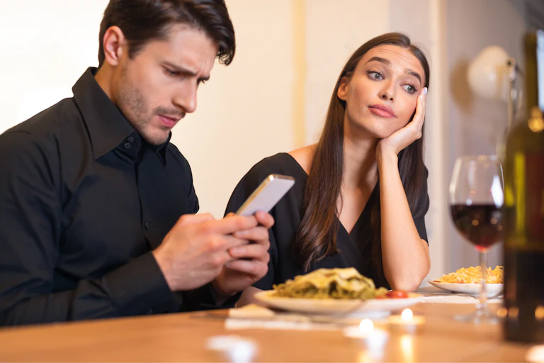 Woman looking bored on a date while her partner is texting.