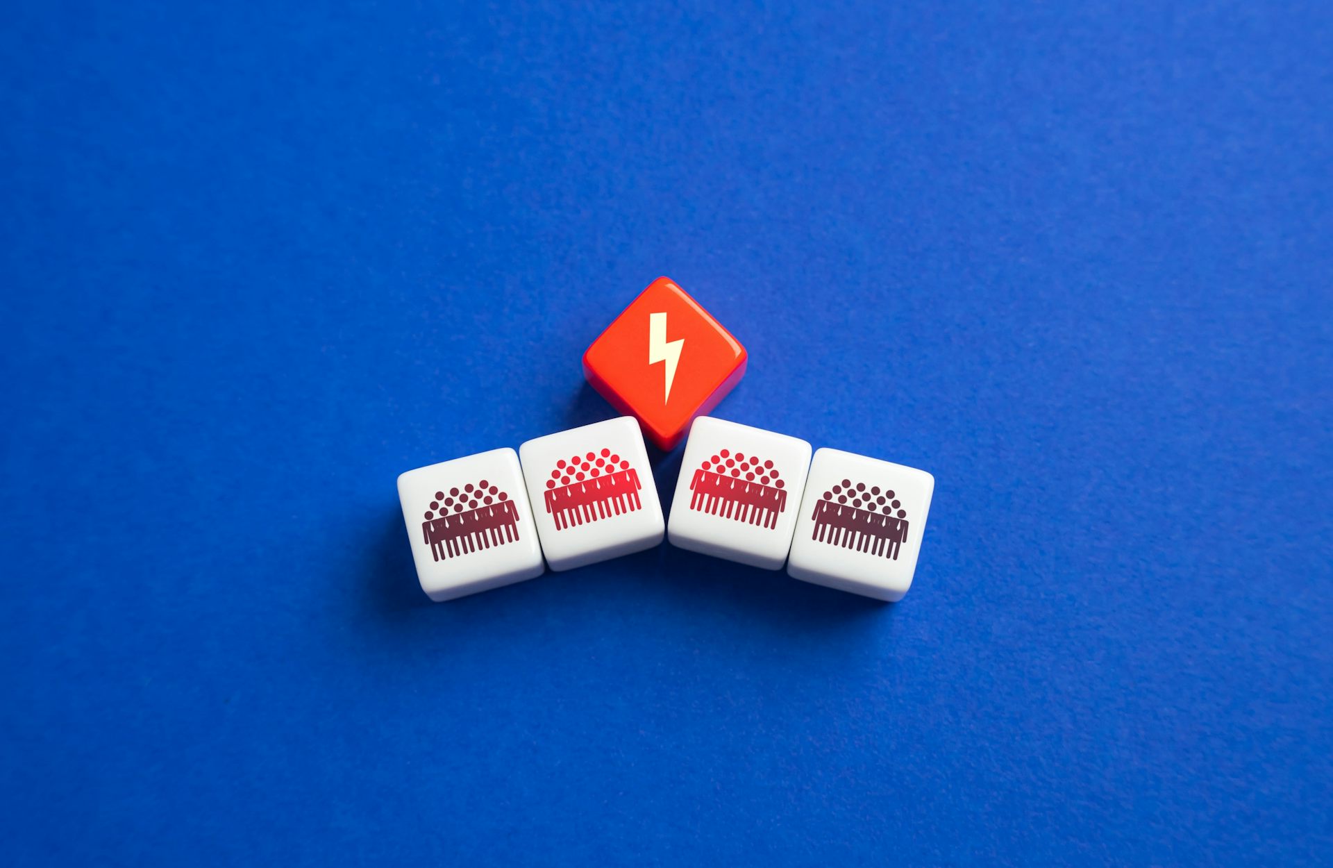 Dos fichas que muestran grupos de personas son separadas por una ficha roja que muestra un rayo en blanco.