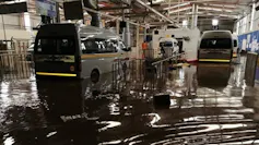 Minibus taxis stand in a factory where the floor is entirely covered by floodwaters.