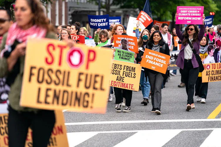 People march holding signs objecting to fossil fuels.