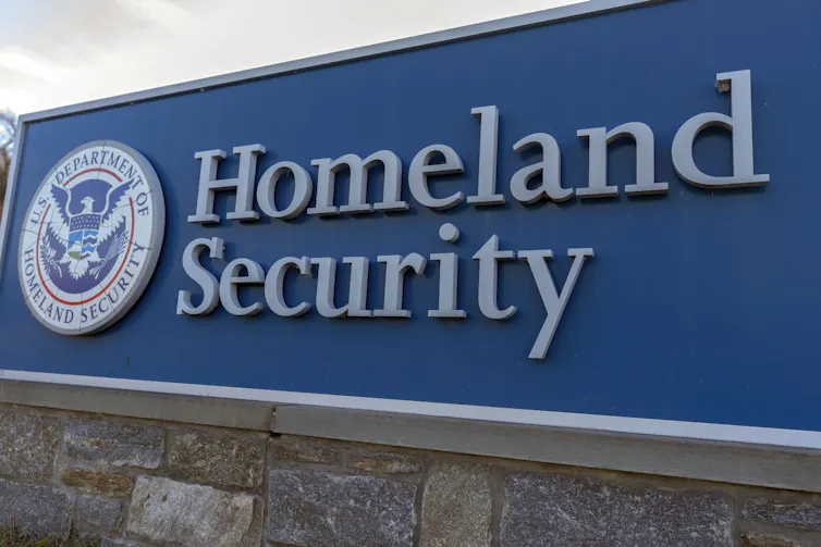 A large outdoor sign with a round logo and text mounted on a stone base.