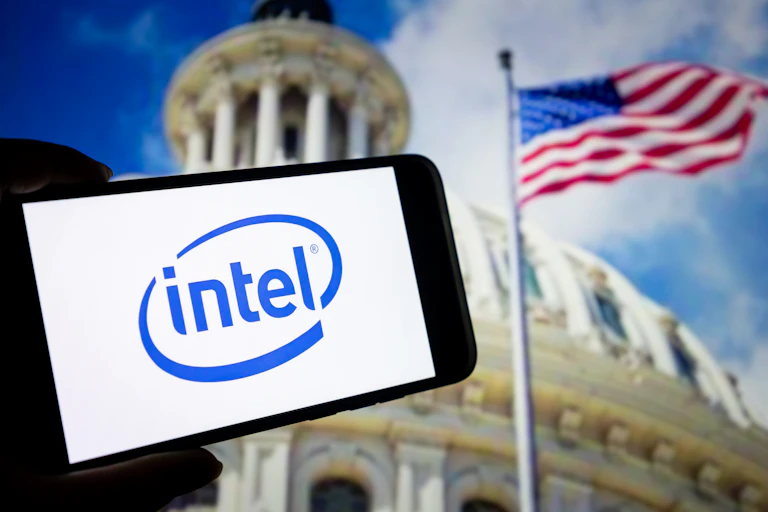 The Intel logo is seen on a smartphone, juxtaposed with an American flag.