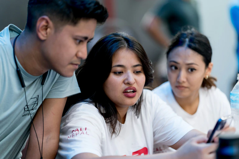 People stare critically at a phone screen.