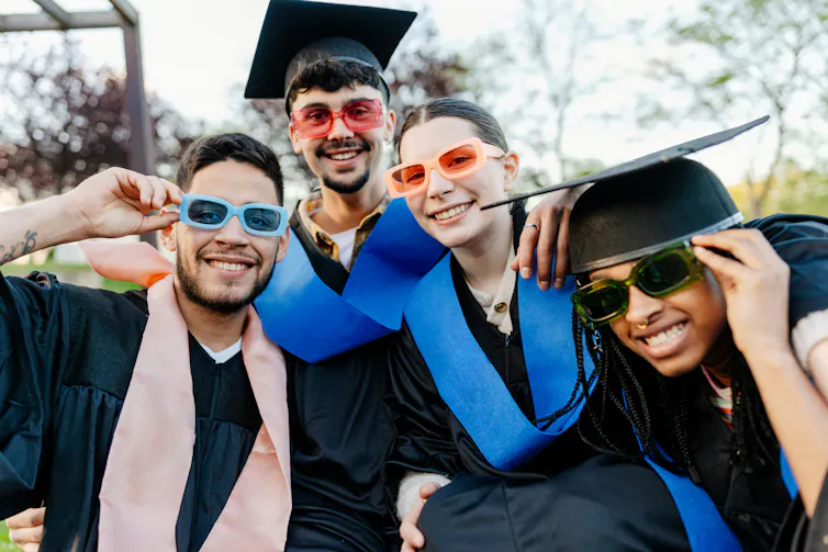 Graduates in gowns wearing sunglasses.