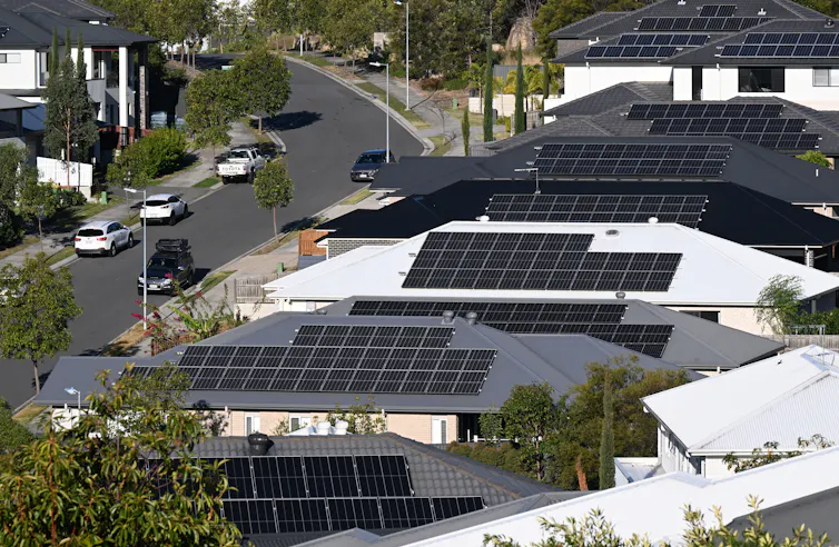 row of houses seen from above with solar panels on their rooftops.