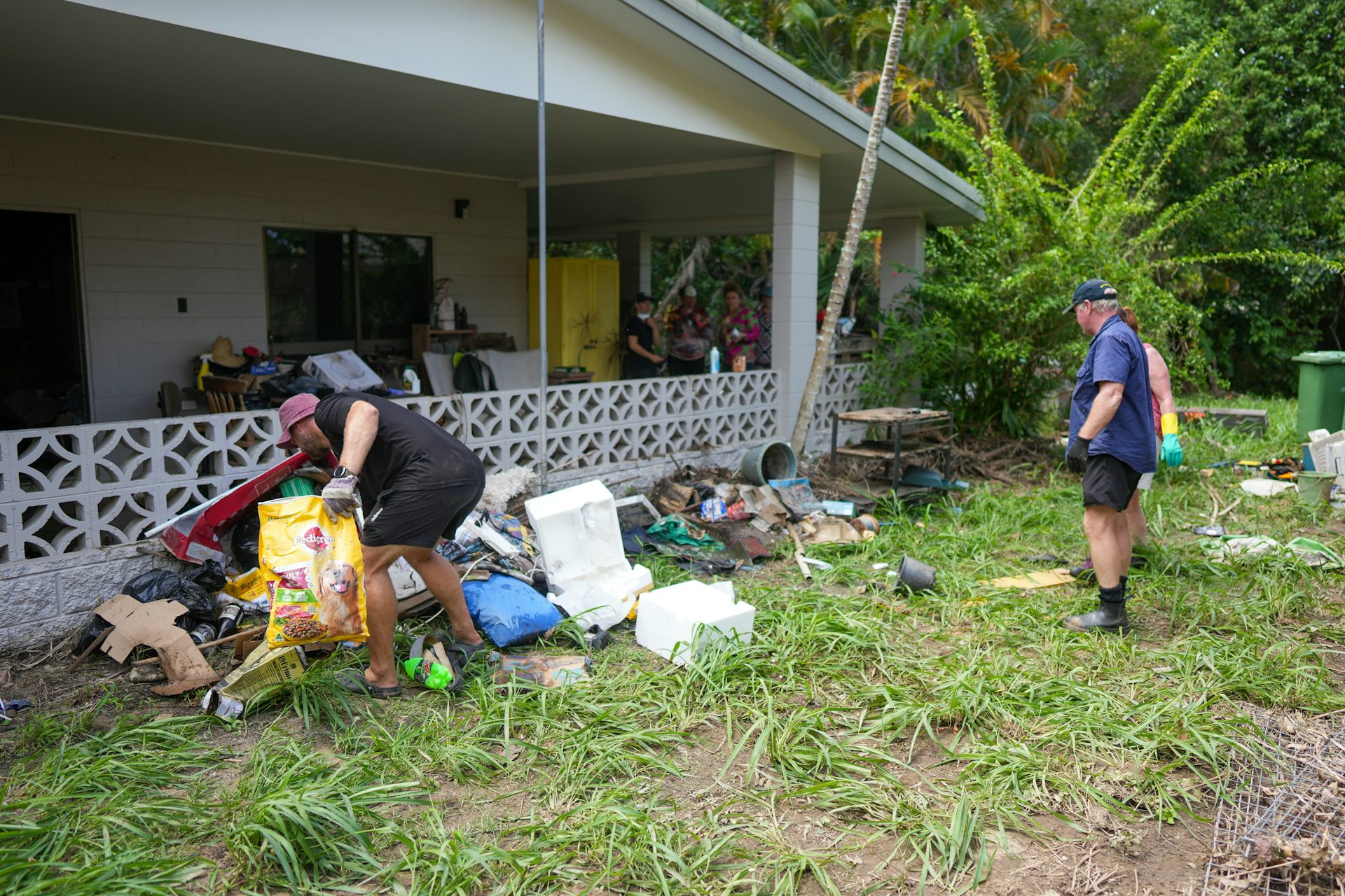 People pick through debris outside a home.