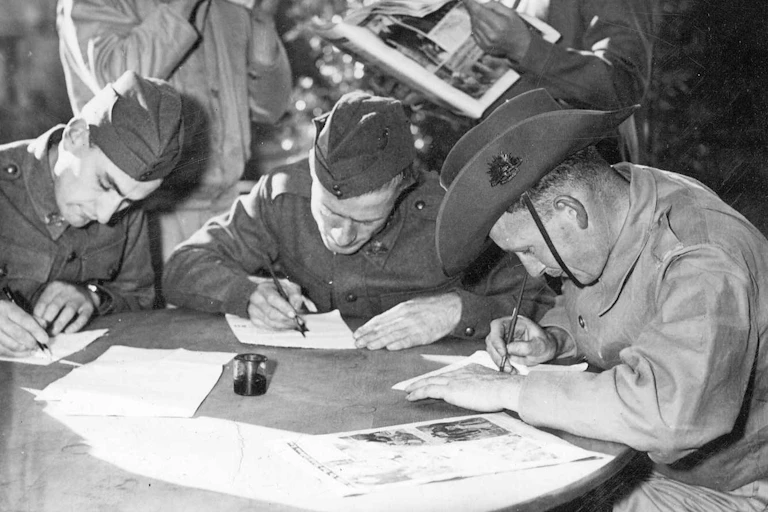 Photo from 1940: three soldiers write letters.