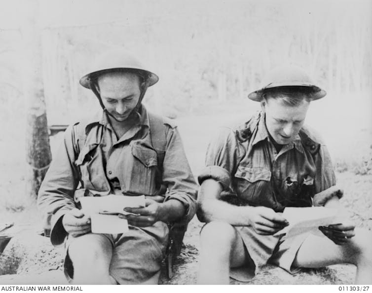 Two young men read letters.