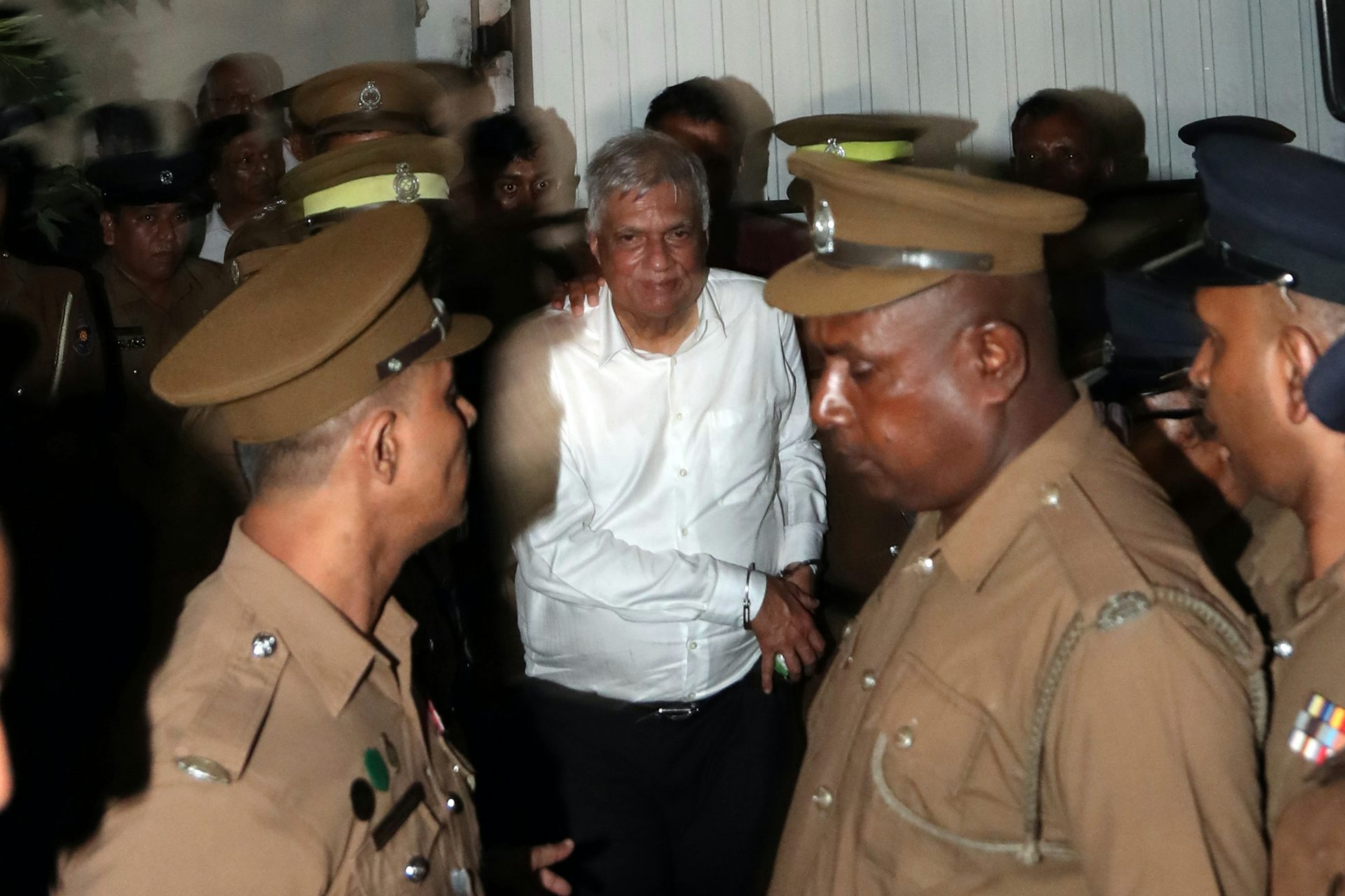 Prison officers escorting a handcuffed Ranil Wickremesinghe.