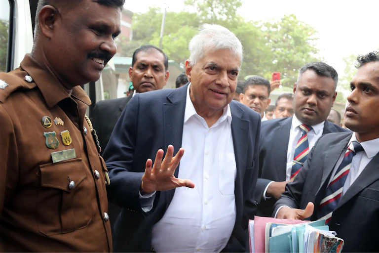 Sri Lankan criminal investigation department officers escort Ranil Wickremesinghe to court.