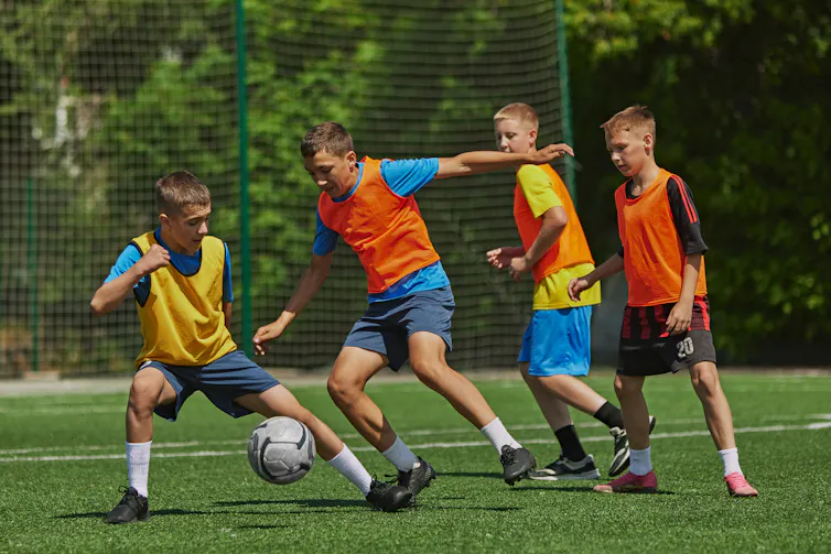 A group of boys plays football outdoors.