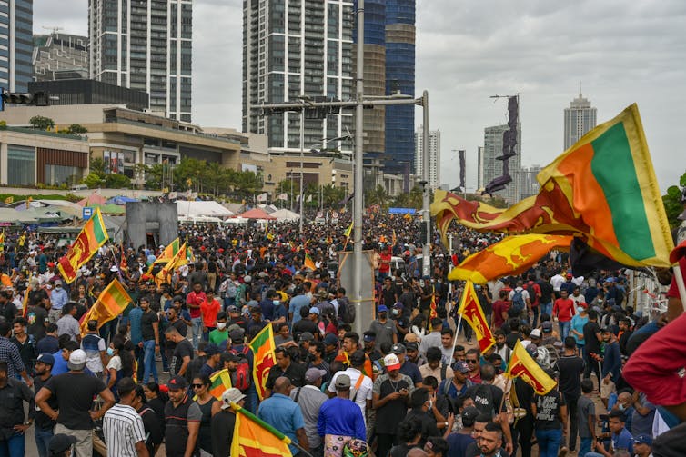 Thousands of Sri Lankans waving flags at a protest.