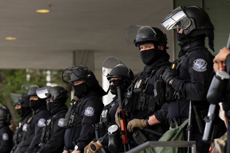 black-clad Customs and Border Protection officers guard a federal building during protests over deportations in Los Angeles.