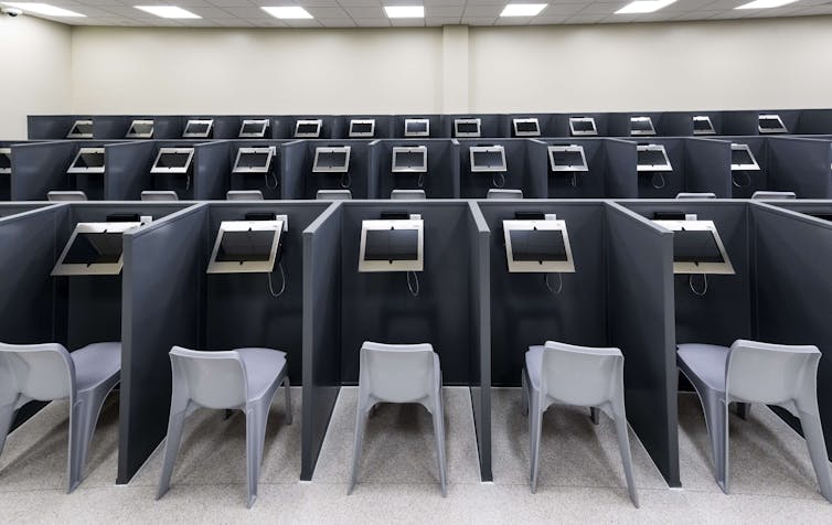 Dozens of stalls which each contain a video monitor and plastic chair