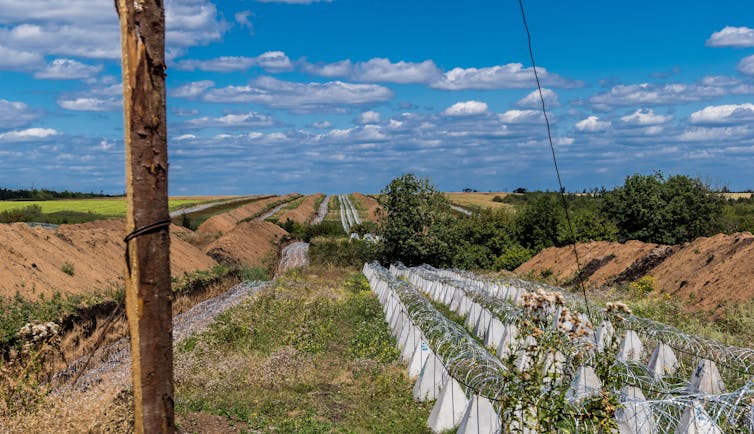 Dragons' teeth and barbed wire beside a trench in eastern Ukraine.