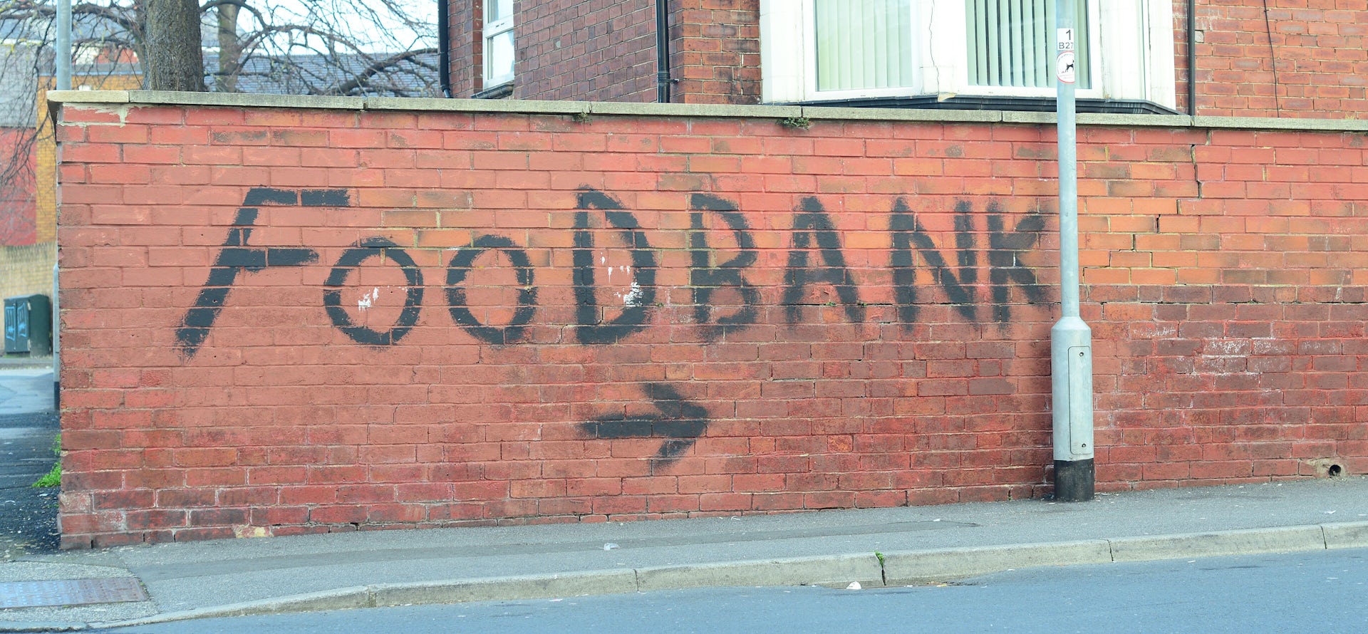 The words 'food bank' painted on a red brick wall.