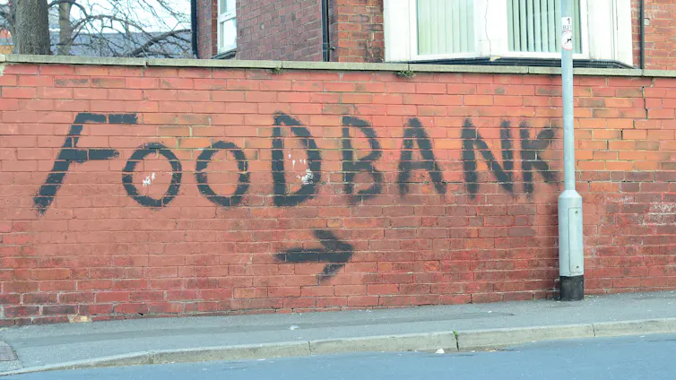 The words 'food bank' painted on a red brick wall.