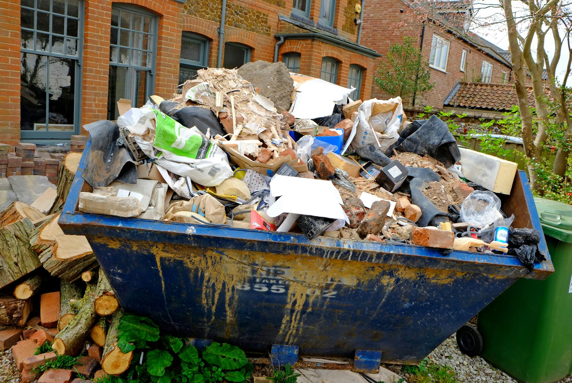 Messy front garden with skip in middle