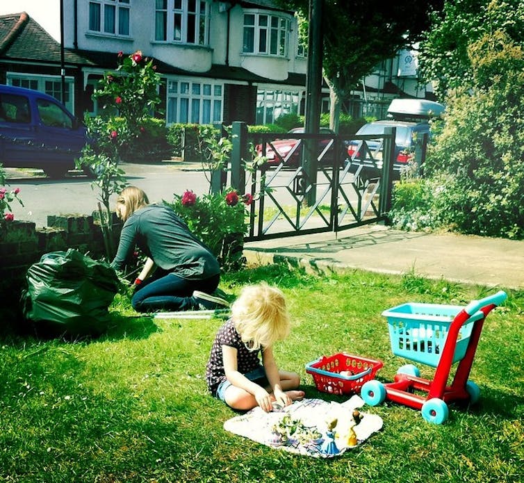 Mother doing gardening while child plays on grass