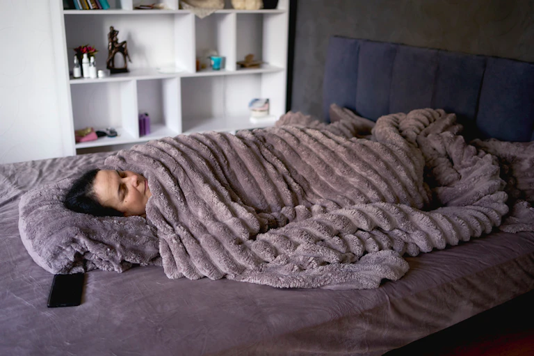 Person sleeping under a heavy blanket.
