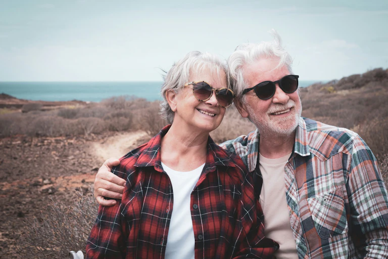 Deux personnes âgées regardent l'horizon en souriant