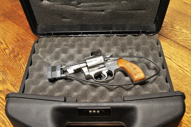 A hand gun with a lock is in a safe box.