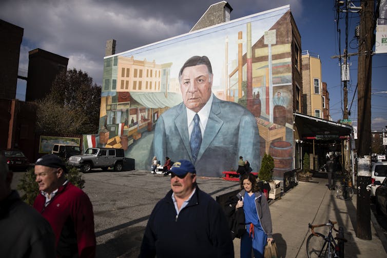 Large mural depicting man in blue suit and tie covers entire side of row home