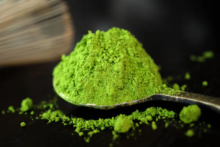 Spoon holding a pile of green powder.