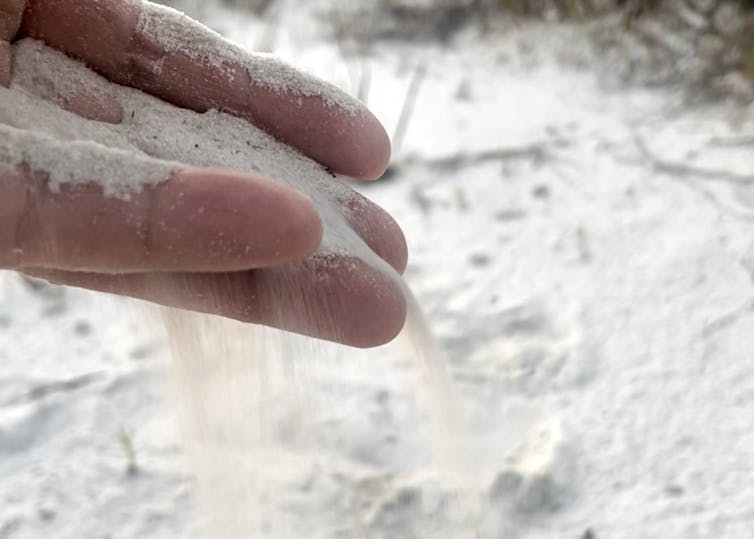 Sand pours through a person's fingers