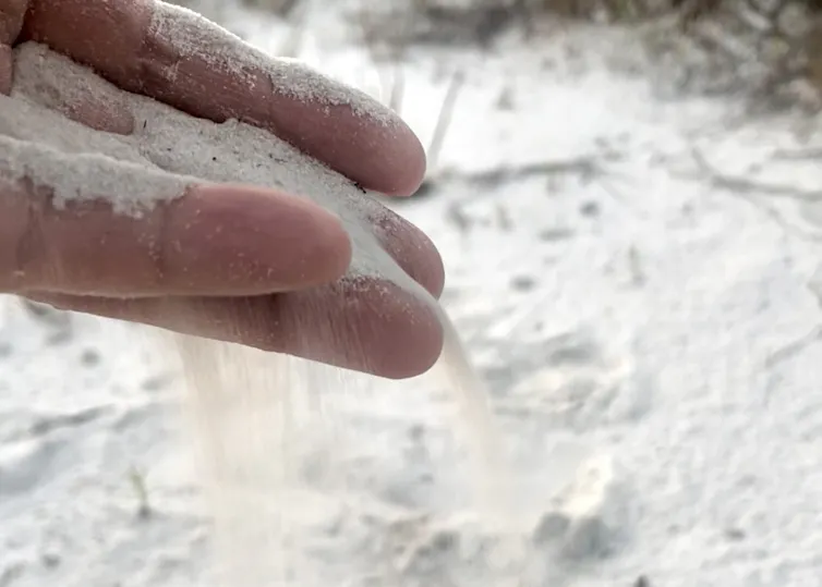 Sand pours through a person's fingers
