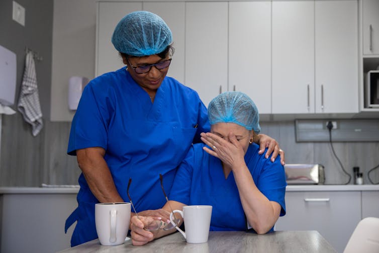 Two healthcare workers comfort each other in emotional stress