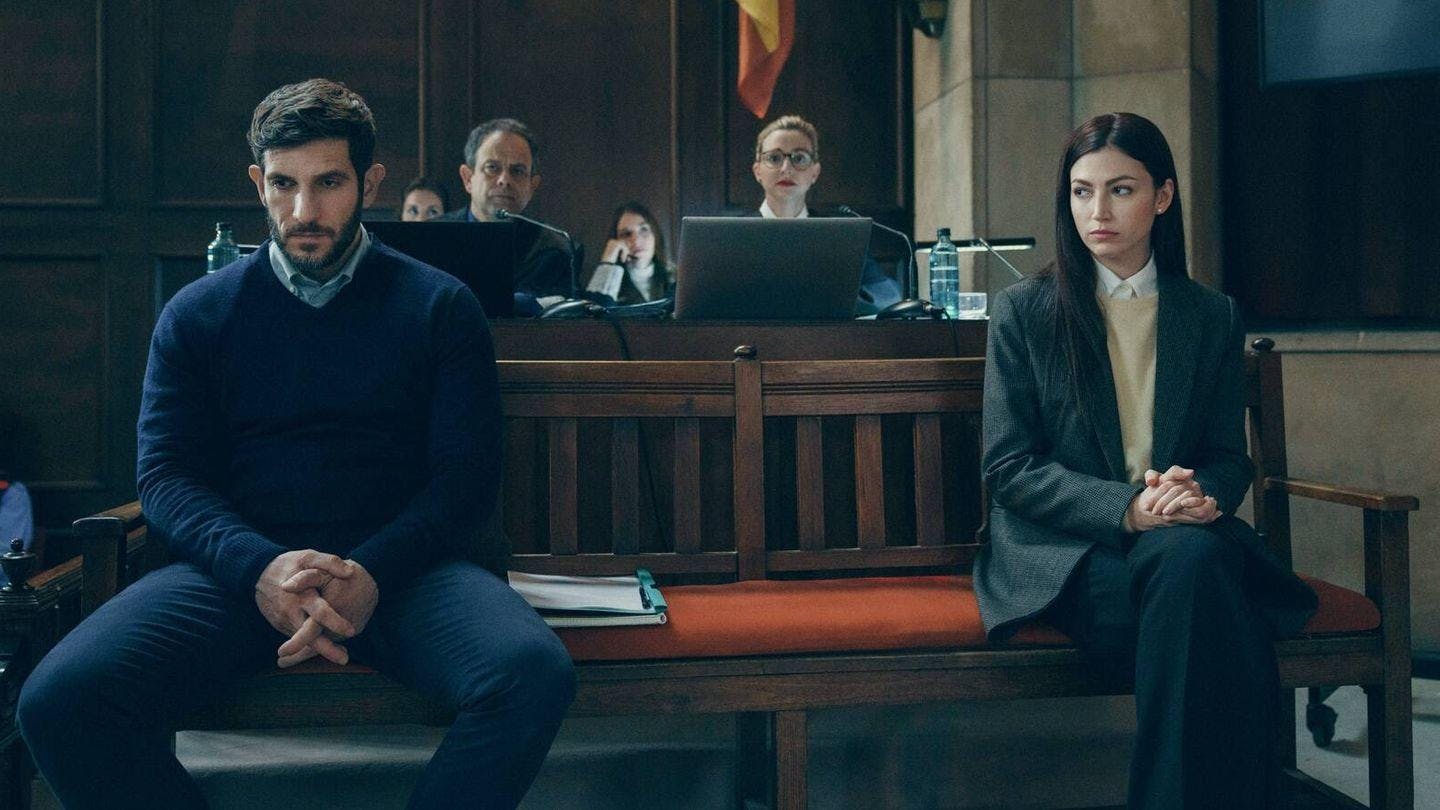 Un hombre y una mujer se sientan, muy separados, en el banco de los acusados en un juicio.
