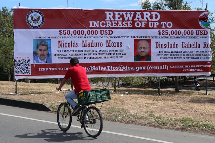 A man looks at a billboard advertising the reward offered by the US government for Maduro and one of his ministers.