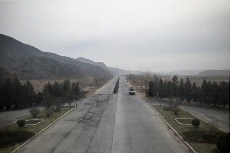 Un camion sur une route déserte qui traverse un paysage triste