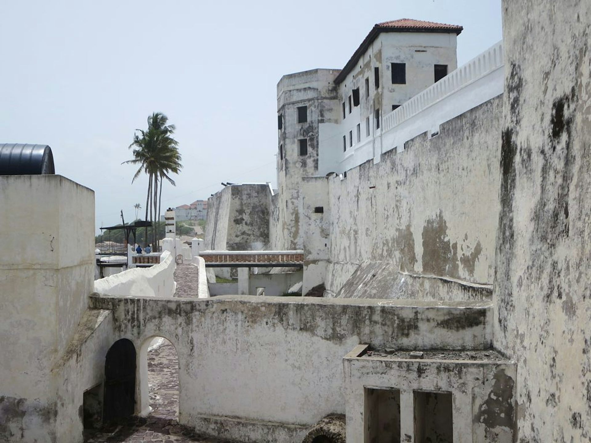 Large old wall and building with palm trees in the distance