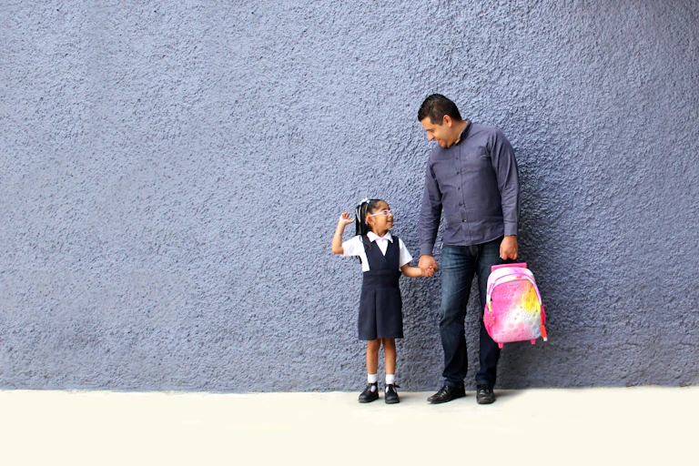Father and small daughter in school uniform