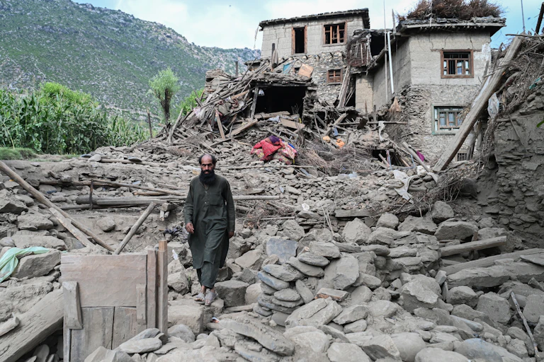 A man walks through the rubble of a house.
