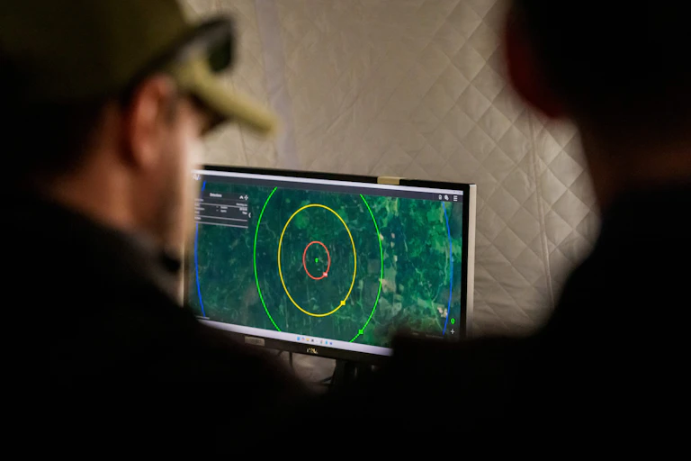 Two men in uniform looking at a computer monitor showing some kind of map