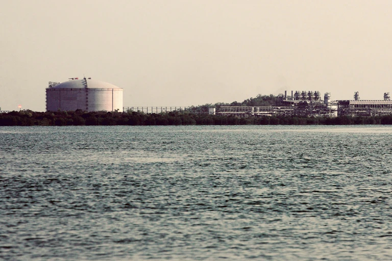 a large gas tank and industrial facility at the shoreline
