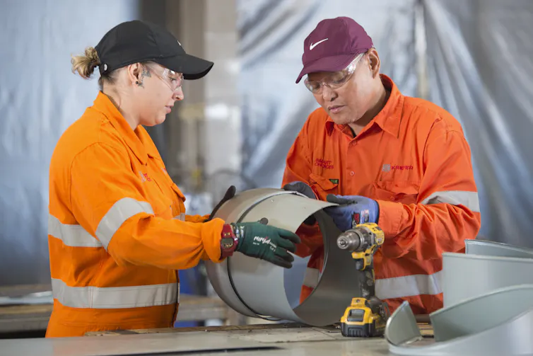 two workers inspecting a pipe