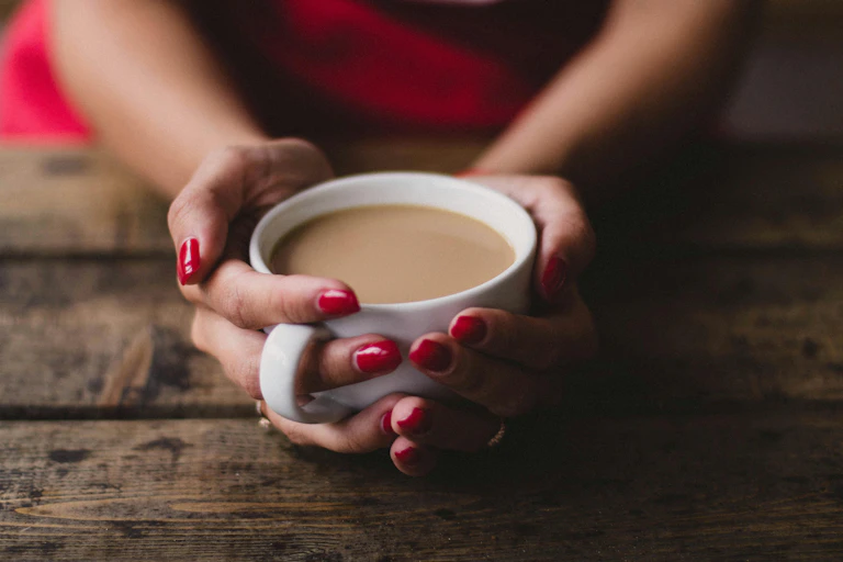 A woman's hands holding a cup of instant coffee.