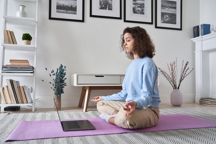 Woman doing guided yoga with her laptop.