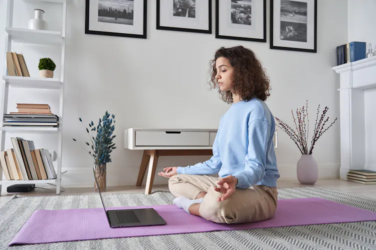 Woman doing guided yoga with her laptop.