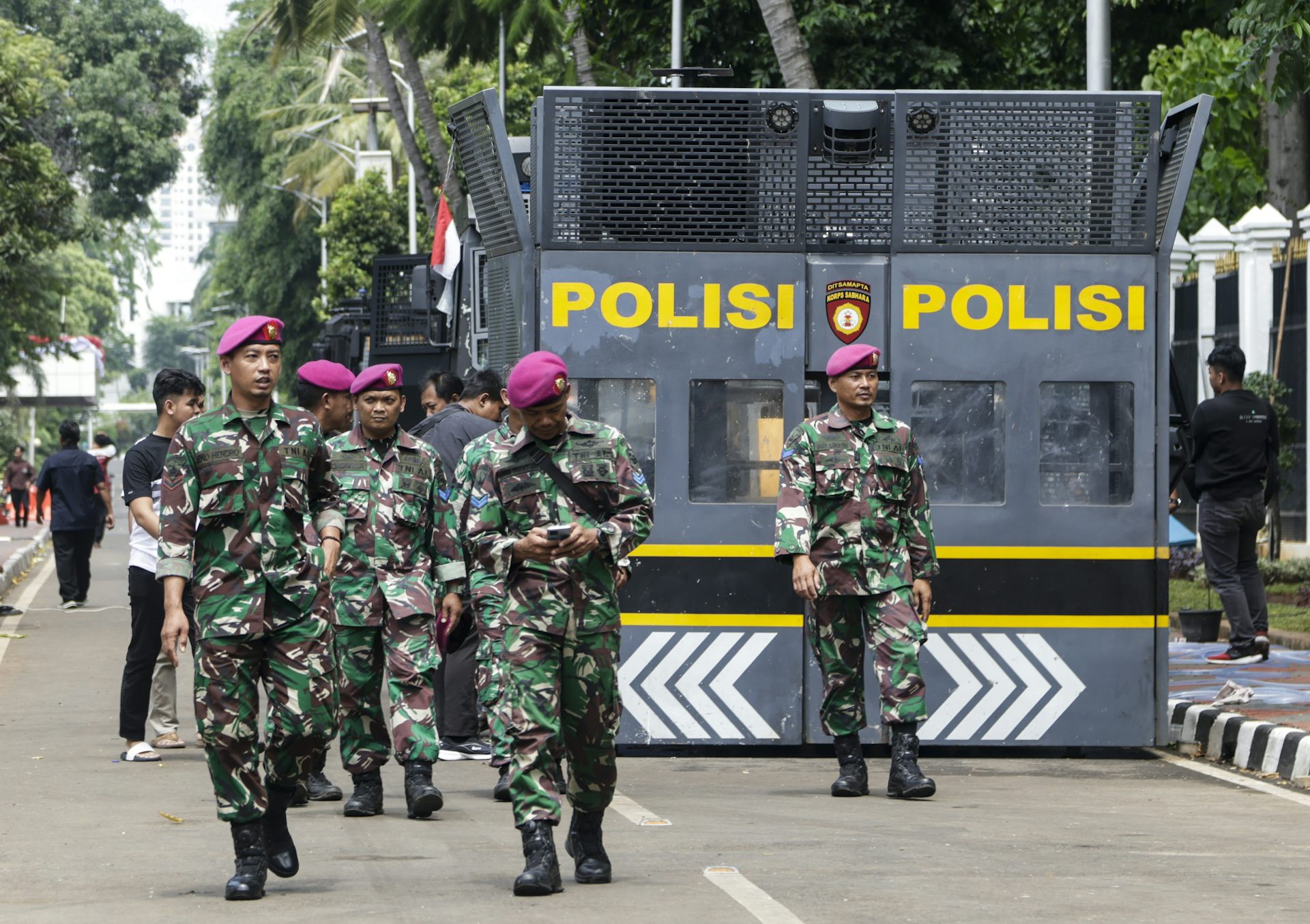 Indonesian army personnel walk past an anti-riot police vehicle.