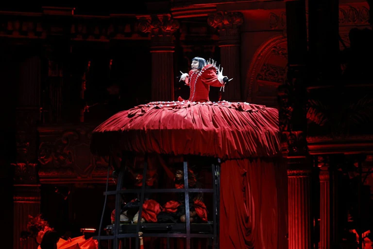 Lady Gaga wearing an enormous red ball gown rises above the stage.