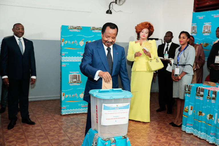 A man wearing grey suits casting his vote