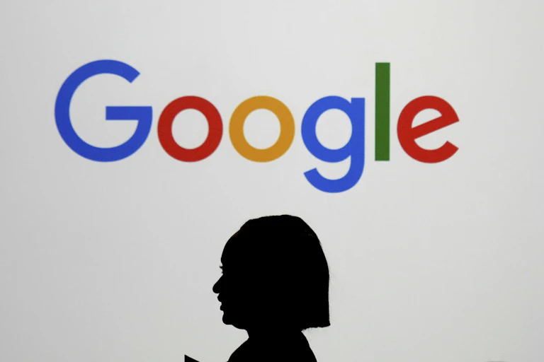 A person walks by a giant screen displaying the colourful Google logo.