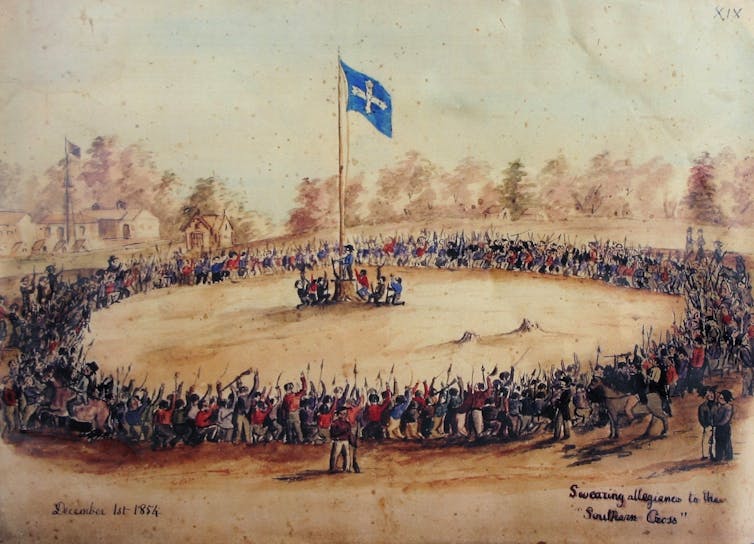 A crowd gathers around the Eureka flag.